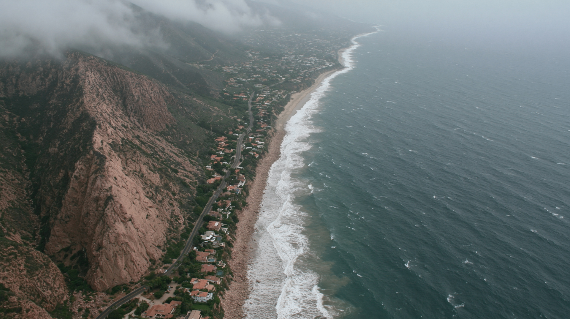 Aerial view of the Malibu coastline with fog rolling over the cliffs